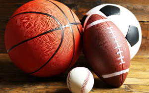  basketball, football, soccer ball, and baseball placed together on wooden floor